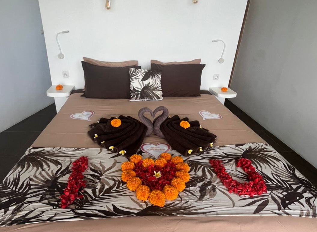 Villa bedroom with king bed and teak ceiling opening onto the pool